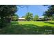 Expansive green field with vintage barn structures and mature trees under a clear sky at 233 Hicks Rd, Statesville, NC 28625