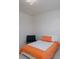 Cozy bedroom features a bed with orange bedding, a modern chair, and minimalist decor at 2407 Baxter Se Pl, Concord, NC 28025