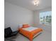 Bedroom featuring a bed with orange bedding and a modern black chair near a bright window at 2407 Baxter Se Pl, Concord, NC 28025