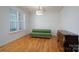 Sunlit living room with hardwood flooring, green sofa, antique dresser, and a window with blinds at 2407 Baxter Se Pl, Concord, NC 28025