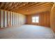 Unfinished room showcasing exposed studs, rafters, and a bright window awaiting customization at 2407 Baxter Se Pl, Concord, NC 28025
