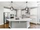 Modern white kitchen featuring stainless steel appliances, a large island, and stylish pendant lighting at 252 Broadleaf Dr, Denver, NC 28037