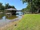 Picturesque lakefront property featuring a dock with a boat lift and lush green surroundings on a sunny day at 2721 Nance Cove Rd, Charlotte, NC 28214