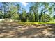 Large grassy backyard surrounded by mature trees and a wooden fence at 411 Patience Dr, Concord, NC 28025