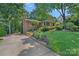 Charming brick home with lush landscaping, mature trees, and a long driveway on a sunny day at 5441 Wintercrest Ln, Charlotte, NC 28209