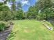 Expansive backyard with a lush lawn, framed by mature trees and an ornamental fence. Basketball court and trampoline in background at 7009 Providence W Ln, Charlotte, NC 28226
