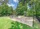 This backyard features a concrete basketball court and trampoline surrounded by lush greenery at 7009 Providence W Ln, Charlotte, NC 28226