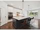 Modern kitchen featuring white cabinets, stainless steel appliances, and a marble island with seating at 7009 Providence W Ln, Charlotte, NC 28226
