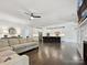 Open concept living room featuring hardwood floors, a ceiling fan, and a view of the modern kitchen at 7009 Providence W Ln, Charlotte, NC 28226
