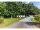 The gravel driveway leads to a house featuring a detached garage surrounded by lush trees at 7032 Waxhaw Hwy, Lancaster, SC 29720