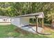 Outbuilding with white siding and partial carport on gravel and grass lot with new gutters at 7032 Waxhaw Hwy, Lancaster, SC 29720
