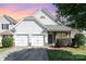 Charming home features a two-car garage, stone accents, and a well-maintained front yard under a colorful sky at 9644 Marquette Nw St, Concord, NC 28027