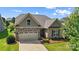Charming home with stone accents, a two-car garage, and a well-maintained lawn and landscaped flower beds at 1108 Mayapple Way, Belmont, NC 28012