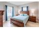 Cozy bedroom with a wooden bed frame, light wood floors, and windows with blue curtains at 307 Stoneyard Rd, Richfield, NC 28137