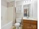 Well-maintained bathroom features a bathtub, oak vanity, decorative mirror and ample overhead storage at 3830 Brookchase Ln, Charlotte, NC 28205