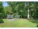 Spacious backyard with green grass, mature trees, swing set, and trampoline at 408 Kennerly Dr, Indian Trail, NC 28079