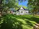 Rear exterior view of the home and the spacious yard, with mature trees providing shade at 409 Everette St, Monroe, NC 28112