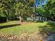 Charming home nestled among mature trees, featuring a lush lawn and inviting covered porch at 409 Everette St, Monroe, NC 28112