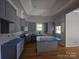 Kitchen with modern gray cabinets, an island, and elegant backsplash, seamlessly flowing into the living space at 409 Everette St, Monroe, NC 28112