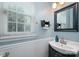 Powder room featuring a modern vanity with dark cabinets, a square mirror, and a window with white blinds at 6422 Gatesville Ln, Charlotte, NC 28270