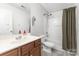 Bathroom with combined tub and shower, white toilet and sink with wood vanity at 9720 Walkers Glen Nw Dr, Concord, NC 28027