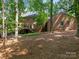 Brick home backyard featuring a deck, mature trees, and natural foliage at 10333 Scott Gate Ct, Charlotte, NC 28277