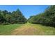 A green, grassy trail leads down a tree-lined path on the property under a clear blue sky at 11056 Us Highway 52 N Hwy, Wadesboro, NC 28170