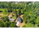 Birds-eye view of a gray home, nestled amongst lush trees, complemented by a green lawn and a quaint neighboring house at 1227 Breezewood Dr, Charlotte, NC 28262