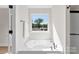 A luxurious soaking tub is positioned beneath a large window offering picturesque views of lush greenery at 1227 Breezewood Dr, Charlotte, NC 28262