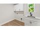 A bright laundry room features a utility sink, shaker cabinets, and a window with a view at 1227 Breezewood Dr, Charlotte, NC 28262