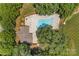 Aerial view of a landscaped backyard with a private pool, patio, and seating areas surrounded by mature trees at 125 Snow Fountain Ln, Mooresville, NC 28115
