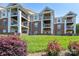 View of condo building with multiple balconies overlooking well-manicured lawn and colorful flowering bushes at 18511 Harborside Dr, Cornelius, NC 28031