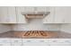 Close up of a modern kitchen cooktop with stainless steel hood and white cabinets at 2143 Barrowcliffe Nw Dr, Concord, NC 28027