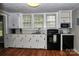 Functional kitchen with white cabinets, black appliances, and bright natural light from multiple windows at 218 Blacksnake Rd, Stanley, NC 28164