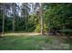 Scenic backyard featuring tall trees and greenery, creating a private, natural outdoor space with a small outbuilding at 5329 E Highway 27 Hwy, Iron Station, NC 28080