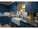 Kitchen featuring blue cabinets, granite countertops, a white ceramic sink, and stainless steel appliances at 5329 E Highway 27 Hwy, Iron Station, NC 28080