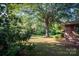 Large front yard with sprawling tree, green lawn, and brick corner of house with red shutters at 5329 E Highway 27 Hwy, Iron Station, NC 28080