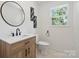 Well-lit bathroom with modern vanity, wood accents, and a round mirror at 5420 Gwynne Ave # 21, Charlotte, NC 28205