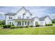 Charming two-story home with a covered front porch, rocking chairs, manicured lawn, and beautiful landscaping at 594 Patterson Farm Rd, Mooresville, NC 28115