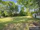Spacious backyard featuring lush lawn, mature trees, and storage shed at 616 W Marion St, Shelby, NC 28150