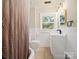 Bathroom featuring wainscotting, stylish light fixture, shower/tub combo, and a window at 616 W Marion St, Shelby, NC 28150