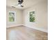 A bright bedroom with hardwood floors, a ceiling fan, and two large windows at 616 W Marion St, Shelby, NC 28150