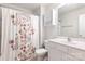 Clean, all-white bathroom featuring a shower with floral curtain and a vanity with storage at 6507 Revolutionary Trl, Charlotte, NC 28217