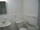 Bathroom featuring tiled walls, comfort-height toilet, pedestal sink, and grab bars at 761 Henry Rhodes Rd, Lincolnton, NC 28092