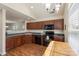 Cozy kitchen featuring wooden cabinets, black appliances, and a view into the adjacent living area at 825 Rock Lake Gln, Fort Mill, SC 29715