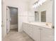 Bright bathroom features a white dual vanity with a large mirror and a doorway leading to the toilet and shower at 8465 Olde Troon Dr, Charlotte, NC 28277