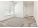 Bright bedroom features neutral carpet, window, and trim with a doorway leading to another room at 8465 Olde Troon Dr, Charlotte, NC 28277