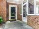 Inviting brick entryway with a storm door and an adjacent glass-enclosed porch at 8465 Olde Troon Dr, Charlotte, NC 28277