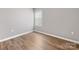Bright bedroom featuring neutral walls, laminate flooring, and a window with blinds, providing a clean, simple aesthetic at 9136 Creedmore Hills Dr, Charlotte, NC 28214
