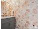Stylish powder room featuring a marble countertop, grey vanity and peach floral wallpaper at 1008 Whipcord Dr, Waxhaw, NC 28173